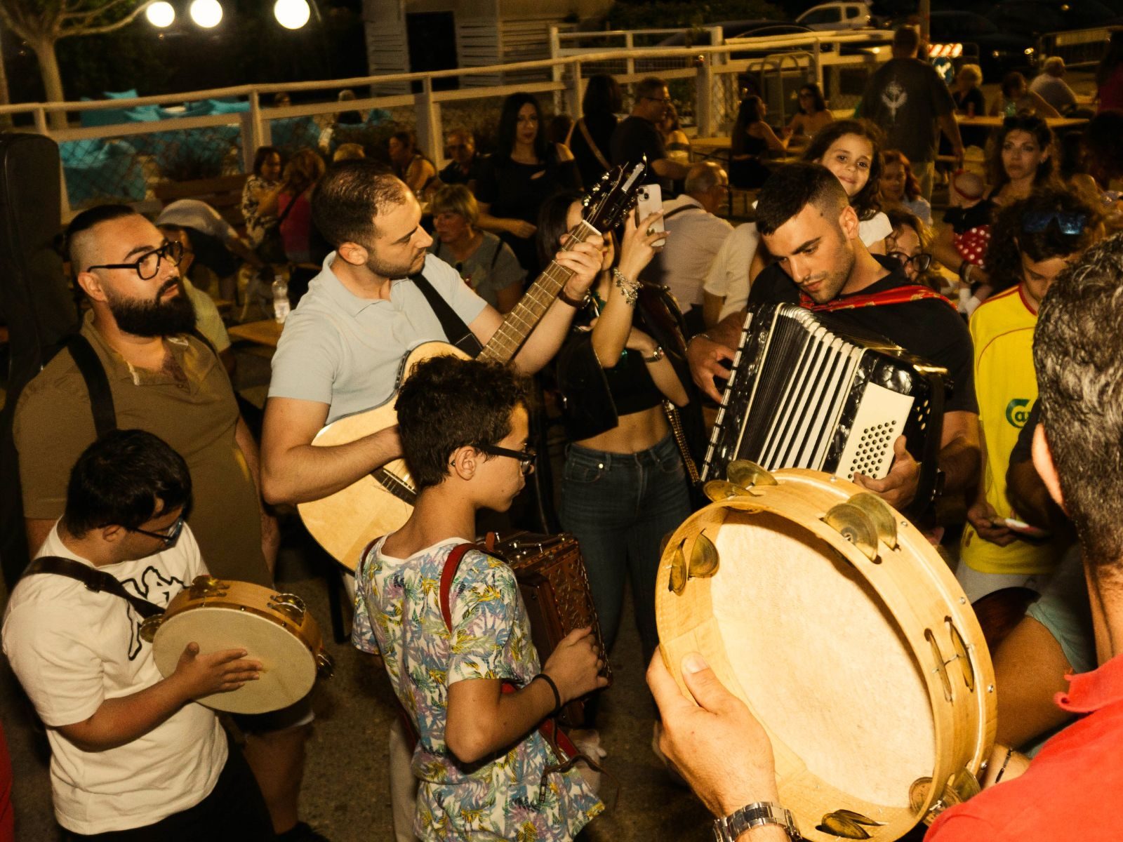 SUNAM - un gruppo di musicisti tra la folla, chitarra, fisarmonica e tamburello